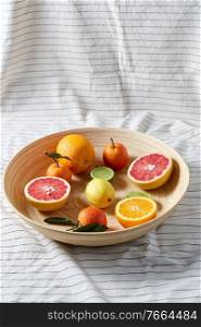 food, healthy eating and vegetarian concept - close up of citrus fruits on wooden plate. close up of citrus fruits on wooden plate