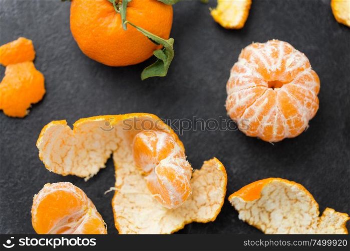 food, healthy eating and vegetarian concept - close up of peeled mandarins on slate table top. close up of peeled mandarins on slate table top