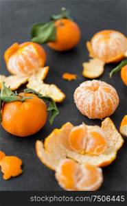 food, healthy eating and vegetarian concept - close up of peeled mandarins on slate table top. close up of peeled mandarins on slate table top