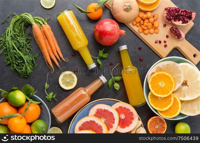 food , healthy eating and vegetarian concept - glass bottles of fruit and vegetable juices on slate table top. glass bottles of fruit and vegetable juices