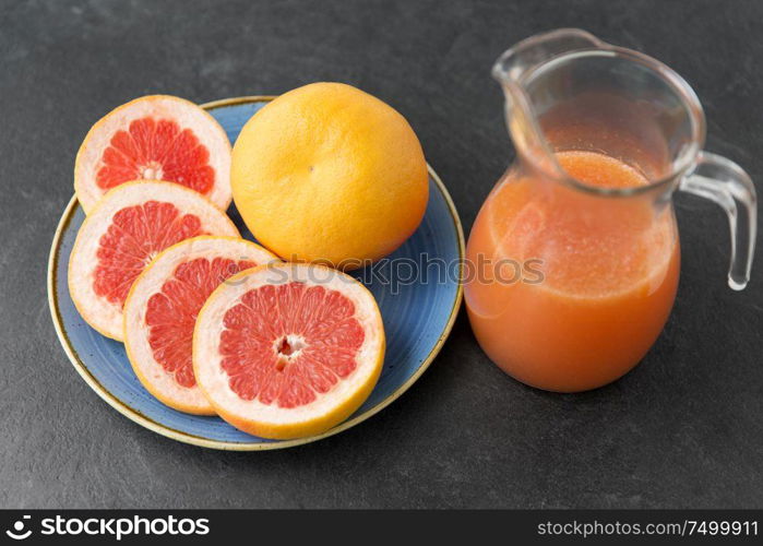 food , healthy eating and vegetarian concept - glass jug of fruit juice with grapefruits on plate. jug of fruit juice with grapefruits on plate