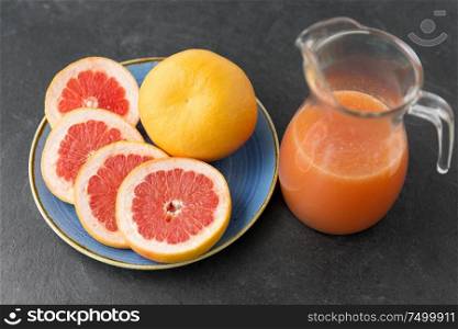 food , healthy eating and vegetarian concept - glass jug of fruit juice with grapefruits on plate. jug of fruit juice with grapefruits on plate