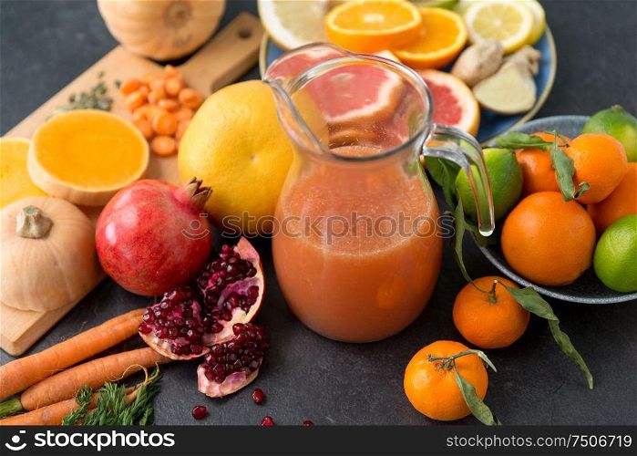 food , healthy eating and vegetarian concept - glass jug of juice with fruits and vegetables on slate table. glass jug of juice with fruits and vegetables