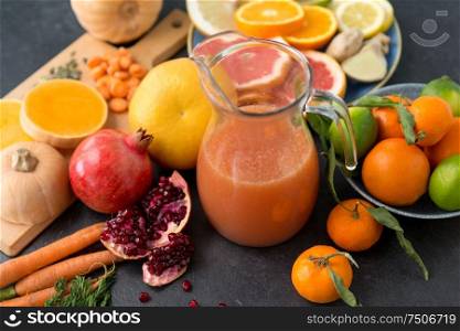 food , healthy eating and vegetarian concept - glass jug of juice with fruits and vegetables on slate table. glass jug of juice with fruits and vegetables