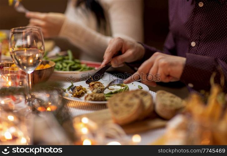 food, holidays and celebration concept - close up of man having christmas dinner and eating meat at home. close up of man eating at christmas dinner at home