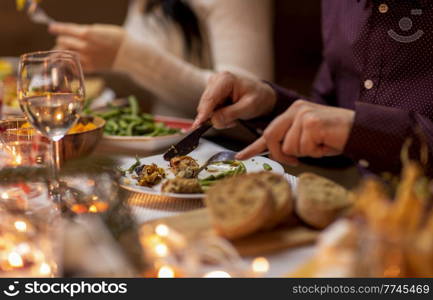 food, holidays and celebration concept - close up of man having christmas dinner and eating meat at home. close up of man eating at christmas dinner at home