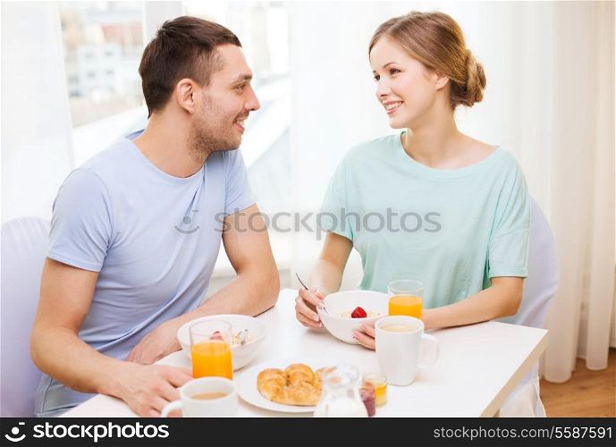 food, home, couple and happiness concept - smiling couple having breakfast at home
