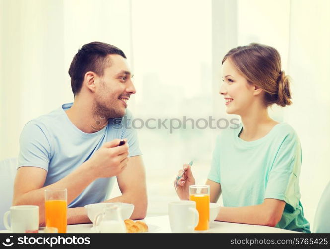 food, home, couple and happiness concept - smiling couple having breakfast at home