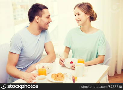 food, home, couple and happiness concept - smiling couple having breakfast at home