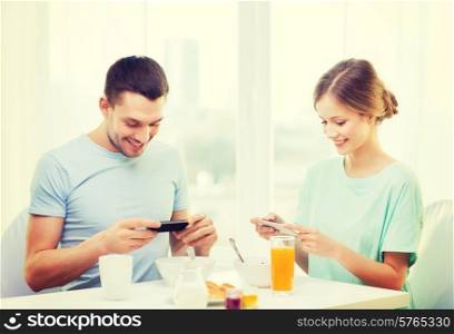 food, home, couple and technology concept - smiling couple with smartphones teaking picture of breakfast at home