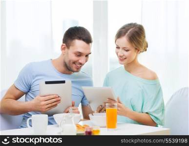 food, home, couple and technology concept - smiling couple with tablet pc reading news and having breakfast at home