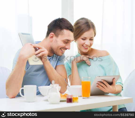 food, home, couple and technology concept - smiling couple with tablet pc reading news and having breakfast at home