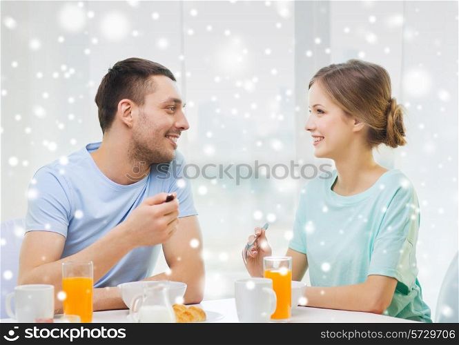 food, home, people and happiness concept - smiling couple having breakfast at home
