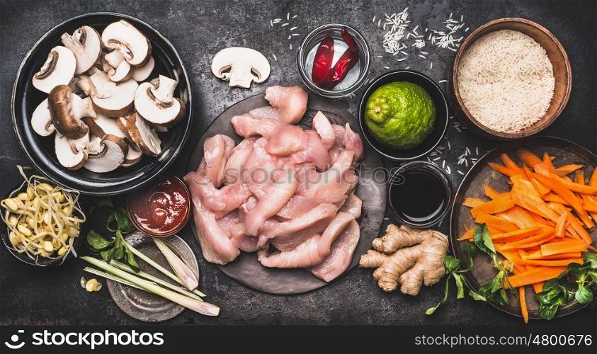 Food ingredients for asian cooking with rice, chicken ,vegetables and spices in bowls, top view