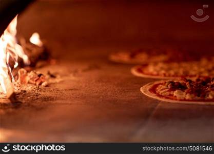 food, italian kitchen and cooking concept - pizza baking in oven at pizzeria. pizza baking in oven at pizzeria