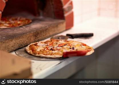 food, italian kitchen, culinary and cooking concept - baked pizza on peel and oven at pizzeria. baked pizza on peel and oven at pizzeria