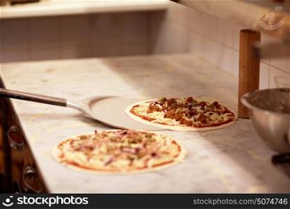 food, italian kitchen, culinary, baking and cooking concept - peel taking pizza off table at pizzeria. peel taking pizza off table at pizzeria