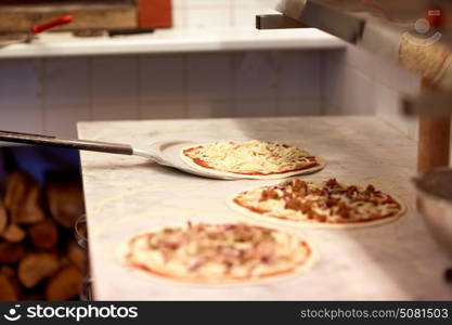 food, italian kitchen, culinary, baking and cooking concept - peel taking pizza off table at pizzeria. peel taking pizza off table at pizzeria