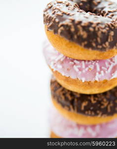 food, junk-food and eating concept - close up of glazed donuts pile over white