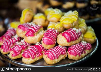 food, junk-food and eating concept - close up of glazed eclair pile on serving tray