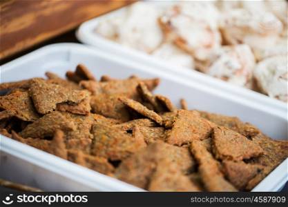 food, junk-food and sweets concept - close up of cookies or bread crisps on serving tray