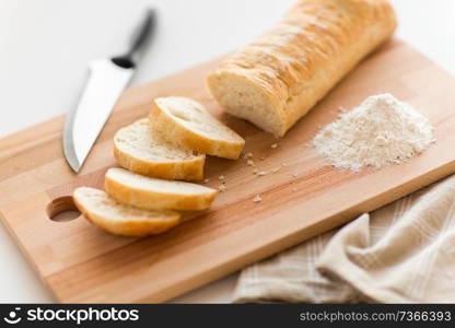 food, junk-food and unhealthy eating concept - close up of white ciabatta bread on wooden cutting board, knife and kitchen towel. close up of white ciabatta bread on cutting board