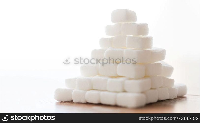 food, junk-food, cooking and unhealthy eating concept - close up of white lump sugar pyramid on wooden table. close up of white lump sugar pyramid on table
