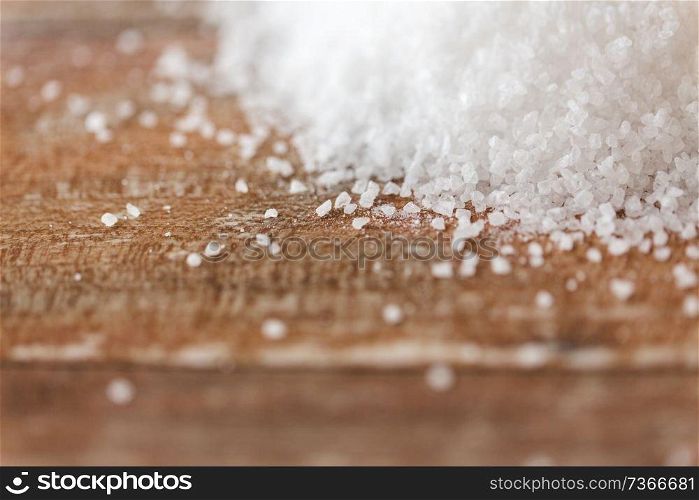food, junk-food, cooking and unhealthy eating concept - close up of white sea salt heap on wooden table. close up of white salt heap on wooden table