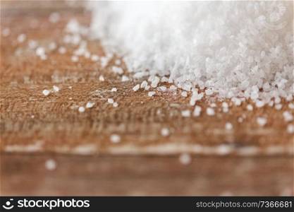 food, junk-food, cooking and unhealthy eating concept - close up of white sea salt heap on wooden table. close up of white salt heap on wooden table