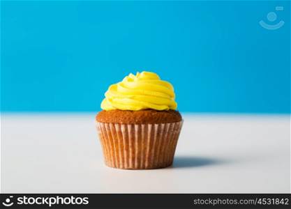 food, junk-food, culinary, baking and eating concept - close up of cupcake or muffin with icing on table