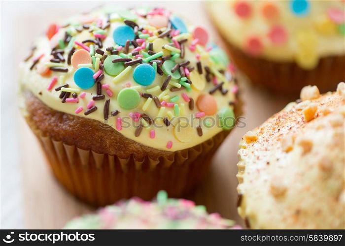 food, junk-food, culinary, baking and holidays concept - close up of glazed cupcakes or muffins on table