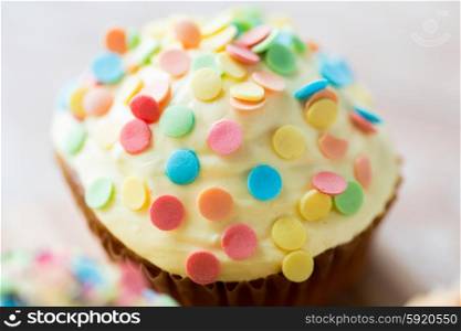 food, junk-food, culinary, baking and holidays concept - close up of glazed cupcake or muffin on table