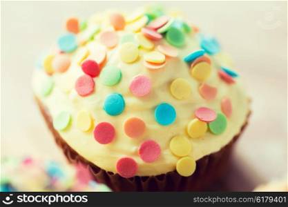 food, junk-food, culinary, baking and holidays concept - close up of glazed cupcake or muffin on table