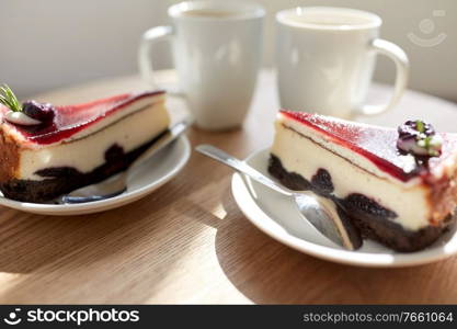 food, junk-food, culinary, baking and holidays concept - piece of delicious cherry chocolate layer cake on saucer with spoon on wooden table. piece of chocolate cake on wooden table