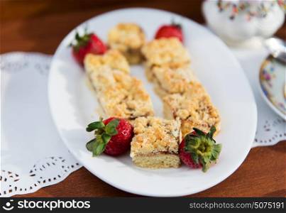 food, junk-food, culinary, sweets and baking concept - pieces of cake or pie and strawberries on plate. pieces of cake or pie and strawberries on plate