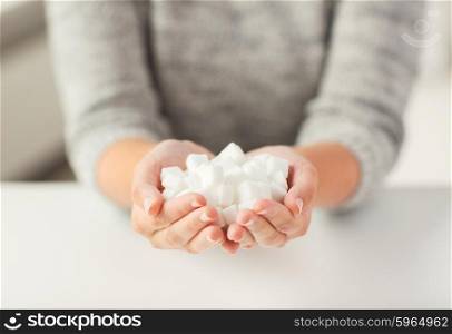 food, junk-food, diabetes and unhealthy eating concept - close up of white lump sugar in woman hands