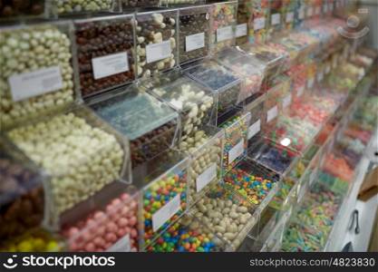 food, junk-food, sell, confectionery and unhealthy eating concept - different sweets in transparent plastic boxes at candy shop. different sweets in boxes at candy shop