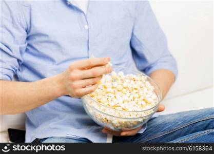 food, junk-food, unhealthy eating and people concept - close up of man eating popcorn at home
