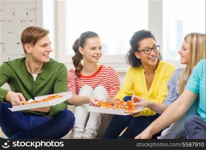 food, leisure and happiness concept - five smiling teenagers eating pizza at home