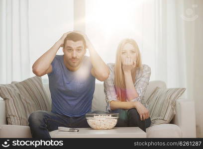 food, love, family, sports, entretainment and happiness concept - upset couple after sports team loss