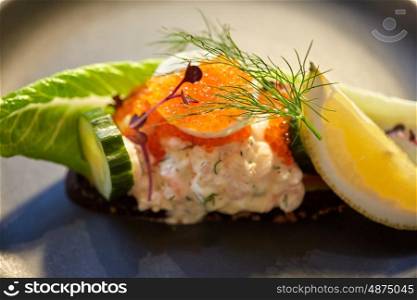 food, new nordic cuisine and cooking concept - close up of toast skagen with shrimps, lemon mayonnaise, caviar and buttery bread on plate