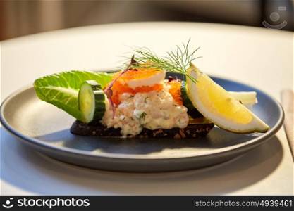food, new nordic cuisine and cooking concept - close up of toast skagen with shrimps, lemon mayonnaise, caviar and buttery bread on plate at restaurant. close up of toast skagen with caviar and bread