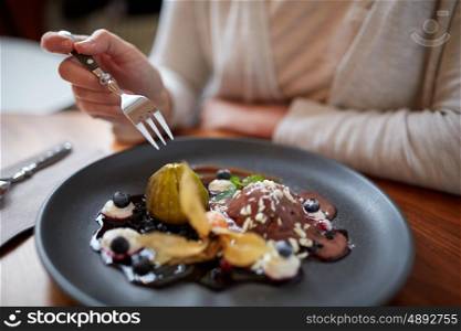 food, new nordic cuisine and people concept - woman eating chocolate ice cream dessert with blueberry kissel, honey baked fig and greek yoghurt at restaurant