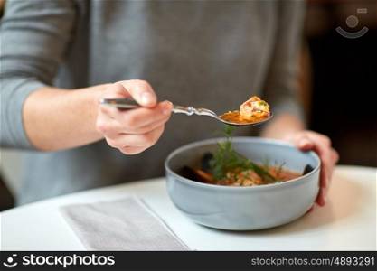 food, new nordic cuisine and people concept - woman eating fish soup at cafe or restaurant