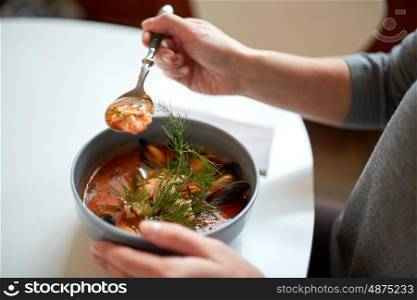 food, new nordic cuisine and people concept - woman eating seafood soup with fish and blue mussels at cafe or restaurant