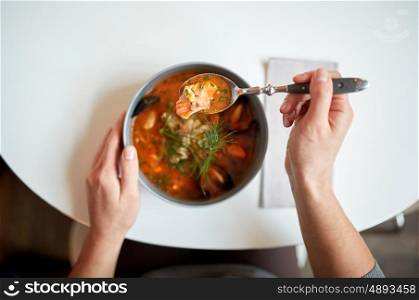 food, new nordic cuisine and people concept - woman eating seafood soup with fish and blue mussels at cafe or restaurant