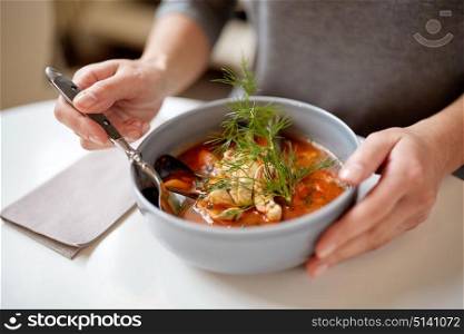 food, new nordic cuisine and people concept - woman eating seafood soup with fish and blue mussels at cafe or restaurant. woman eating seafood soup at restaurant