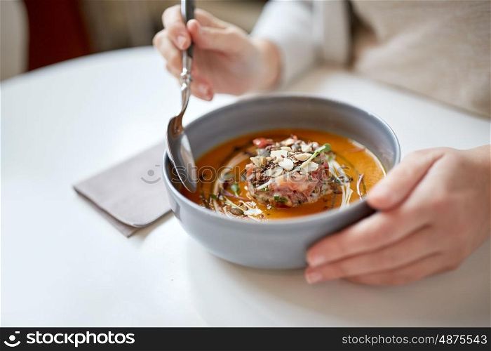 food, new nordic cuisine and people concept - woman eating vegetable pumpkin-ginger cream soup with goat cheese and tomato salad with yogurt in bowl at cafe or restaurant