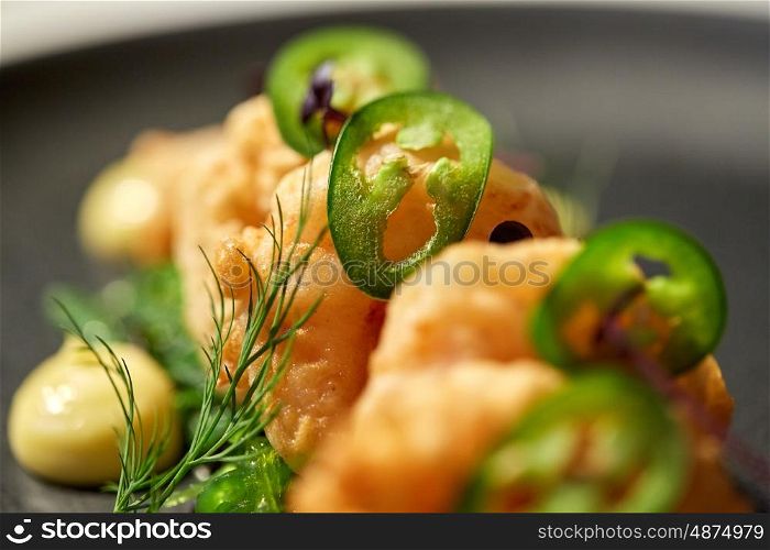 food, new nordic cuisine, culinary and cooking concept - close up of king prawns with jalapeno on plate