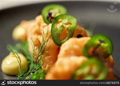 food, new nordic cuisine, culinary and cooking concept - close up of king prawns with jalapeno on plate